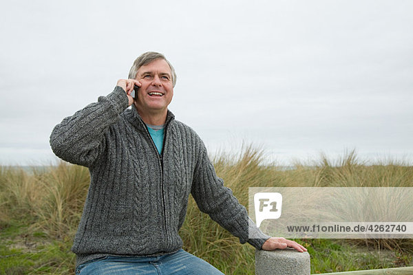 Mann an der Küste auf dem Smartphone