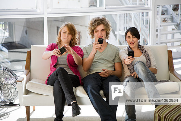 Three teenage friends looking at smartphones