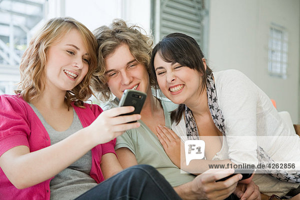 Three teenage friends looking at smartphone