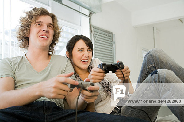 Teenage couple playing with games consoles