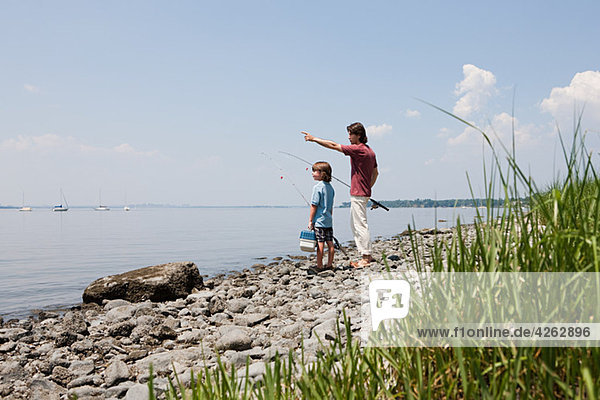 Vater und Sohn am Strand mit Angelruten