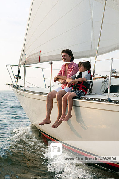 Father and son sitting on yacht