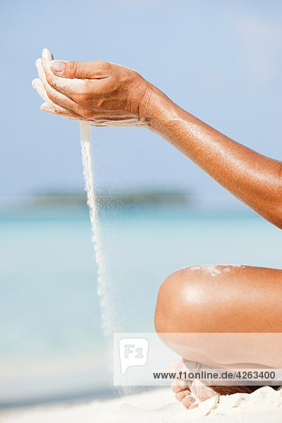 Woman letting sand flow through hands  Maldives
