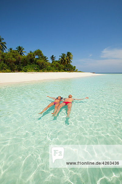 Couple floating in the sea  Baughagello Island  South Huvadhu Atoll  Maldives