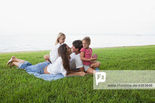 Familie entspannt auf Rasen am Meer