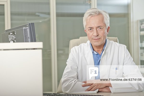 Arzt sitzt hinter dem Schreibtisch