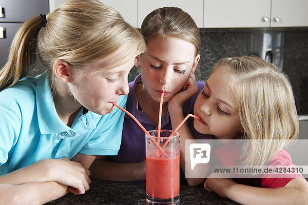 Mädchen trinken Fruchtsaft mit Strohhalmen