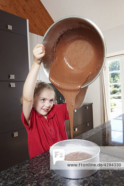 Mädchen gießen Kuchenmischung in die Kuchenform