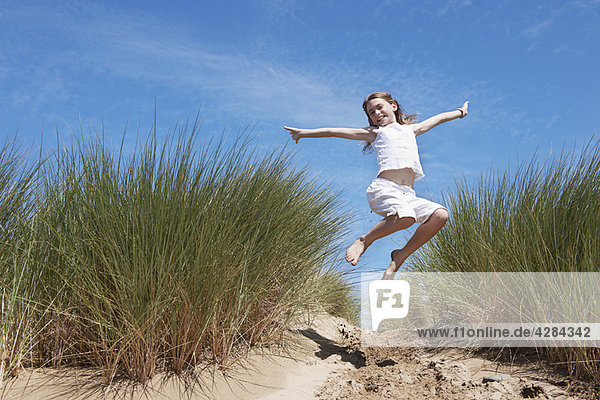 Junges Mädchen beim Springen in Sanddünen