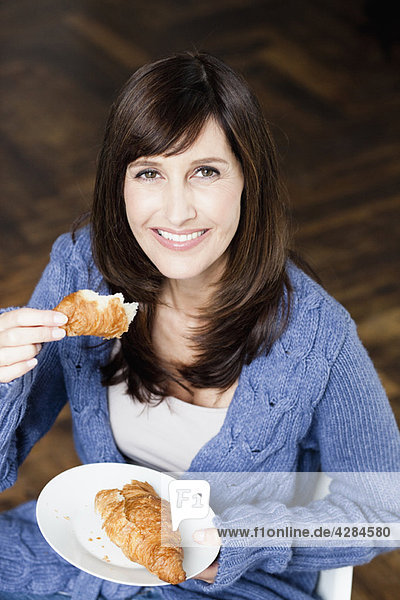 Frau isst Croissant