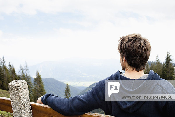 Mann sitzt auf der Bank und beobachtet die Landschaft
