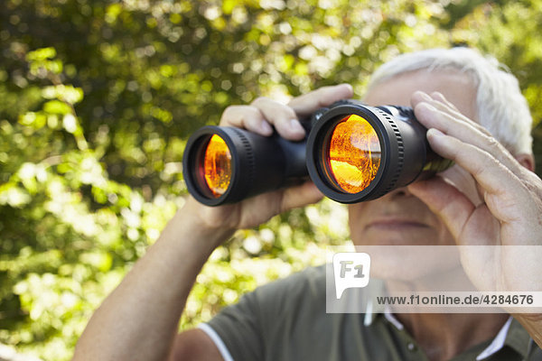 Senior man looking through binoculars