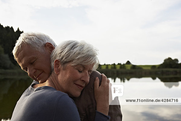 Senior couple hugging in front of lake
