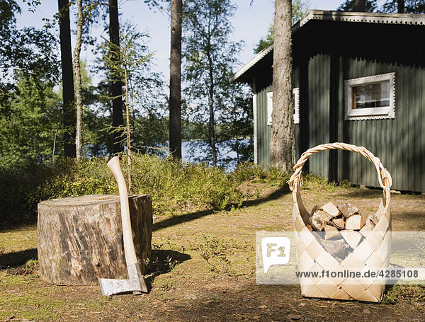 Axe and firewood by wooden cabin