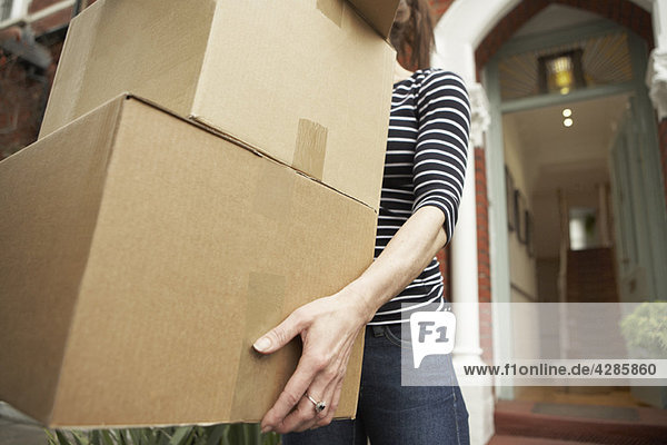 Frau trägt braune Schachteln aus dem Haus