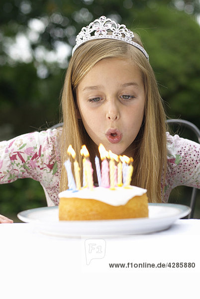 Junges Mädchen bläst Kerzen auf Kuchen aus.