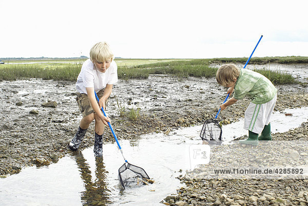 Zwei Jungen spielen im Strom mit Netzen