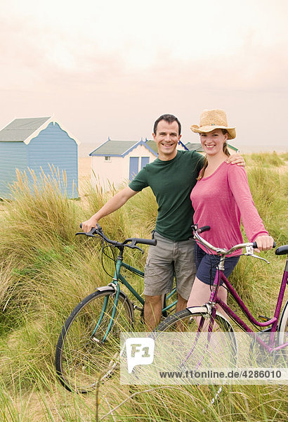 Glückliches Paar mit Fahrrädern am Strand
