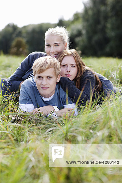 Three young persons laying in grass