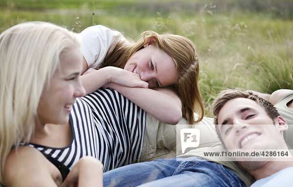 Three young persons laying in grass