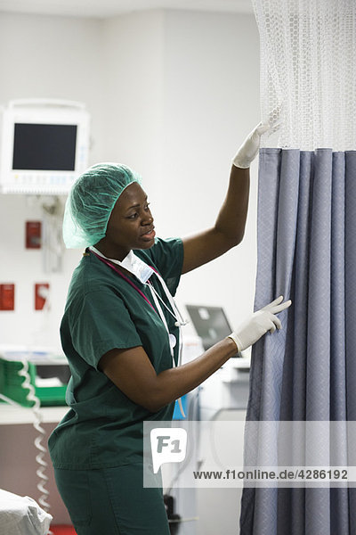 Krankenschwester schließt Vorhang im Krankenhauszimmer