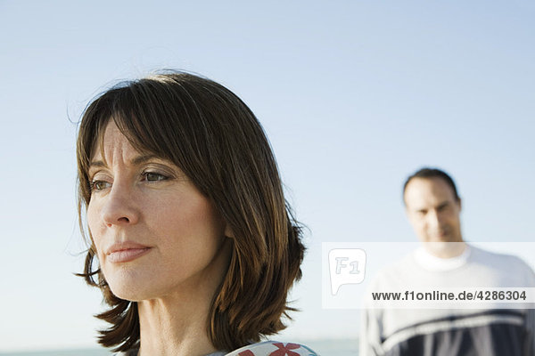 Woman looking away with furrowed brow  man in background