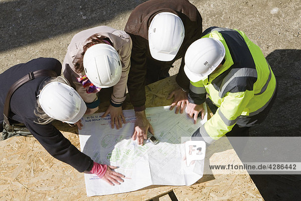 Architektengespräch mit dem Bauunternehmer auf der Baustelle zur Überprüfung der Entwürfe