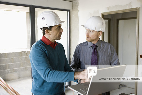 Bauunternehmer und Geschäftsmann mit Laptop auf der Baustelle