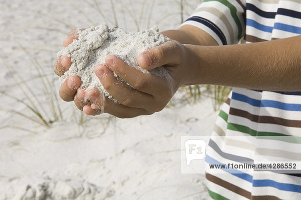 Kind schaufelt Sand mit den Händen