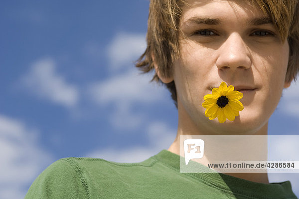Junger Mann mit Blume im Mund  Portrait