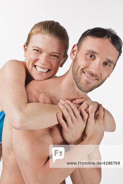 Mann mit Frau hinter umarmt um seinen Schultern