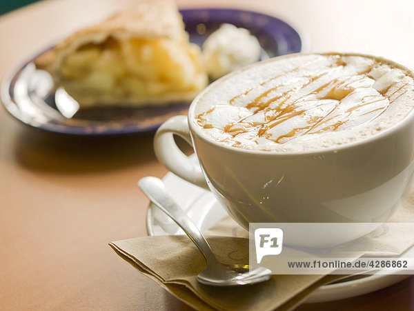 Kaffeetasse mit Löffel  geringe Tiefenschärfe Dessert im Hintergrund