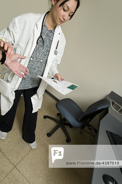 Ärztin Patienten Puls beim betrachten Patienten Diagramms in Krankenhaus Untersuchungsraum  Toronto  Ontario