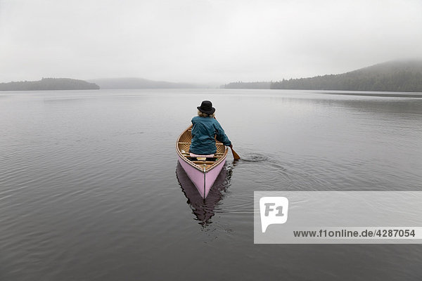 Senior woman canoeing solo on a misty morning  Algonquin Park  Ontario