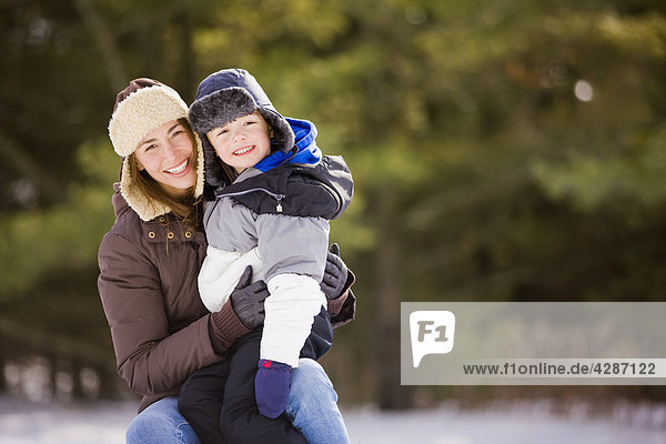 Portrait 30s woman with her 6 year old son outdoors in winter  Scanlon Creek Conservation Area  Bradford  Ontario