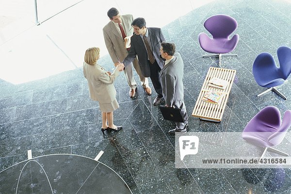 Businesswoman greeting businessmen in lobby  high angle view