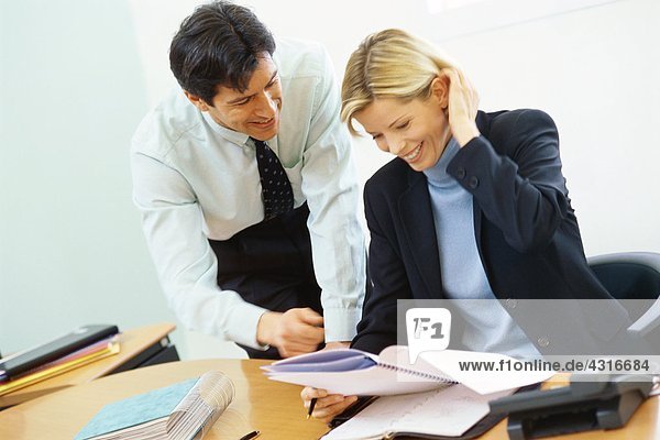 Business colleagues  man leaning over woman's shoulder  pointing to documents