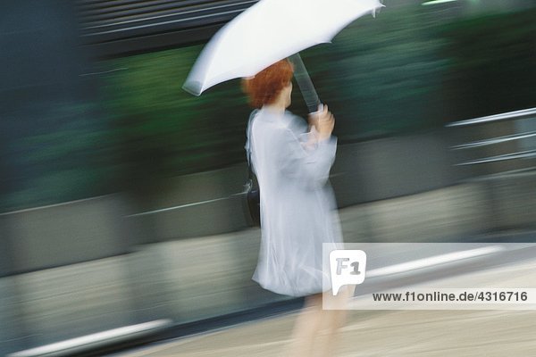 Geschäftsfrau beeilt sich mit Regenschirm