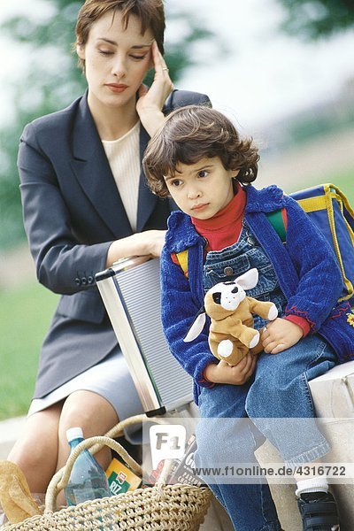 Businesswoman sitting with son  holding head