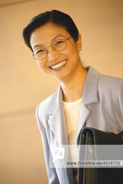 Businesswoman standing with briefcase underarm  portrait