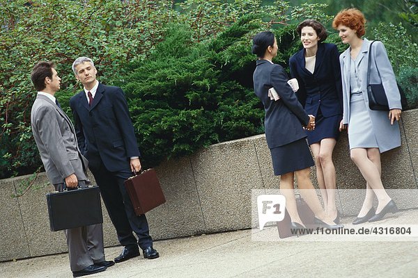 Business executives standing outdoors in groups  chatting