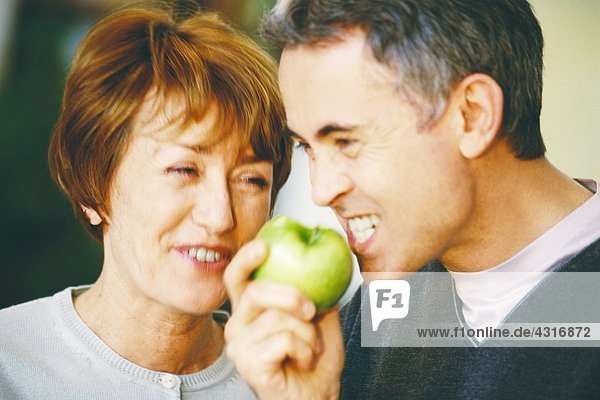 Senior Mann isst Apfel  Seniorin lacht  Nahaufnahme