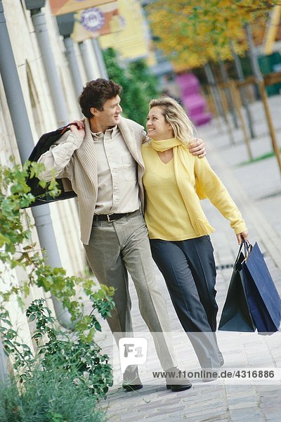 Mature couple walking with shopping bags  full length