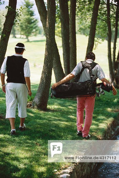 Golfer auf der Suche nach einem Ball unter Bäumen  Rückansicht