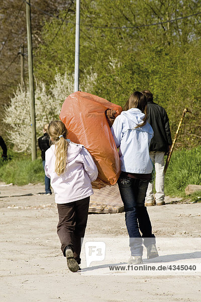 Girls carrying garbage bag together