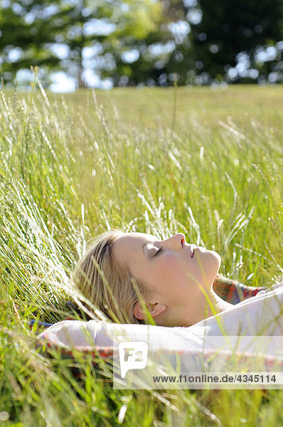 Junge Frau schlafend im hohen Gras