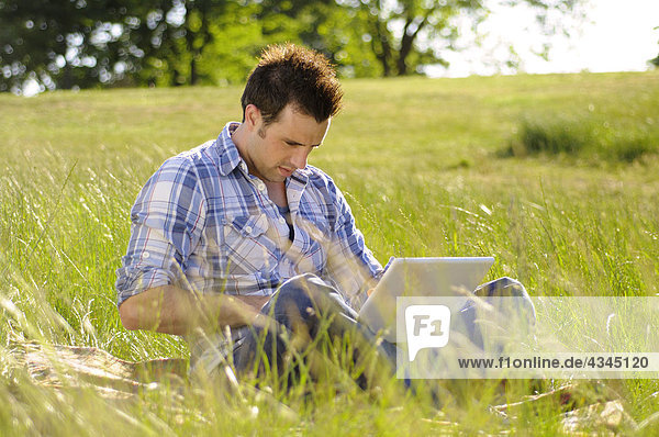 Young man using laptop computer in park