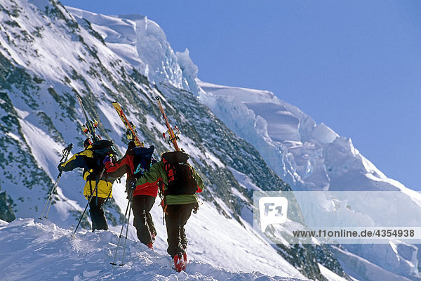 Extreme skiers climbing Ruth Glacier carrying skis Denali National Park AK Range Alaska Spring IN