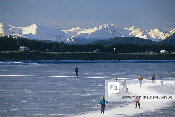 Ice skaters on Twin Lakes along Egan Expressway Juneau Alaska Southeast Winter w/Chilkat Range