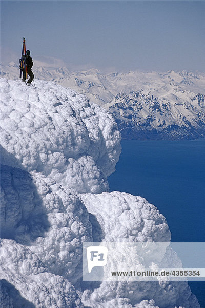 Mountaineer Standing on ridge viewing vast scenery from Augustine Volcano across Cook Inlet Alaska